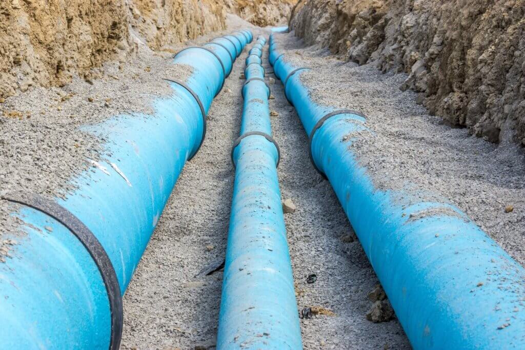 Blaue Wasserrohre in einer Erdausgrabung, symbolisieren moderne Infrastruktur und effiziente Wasserversorgung.