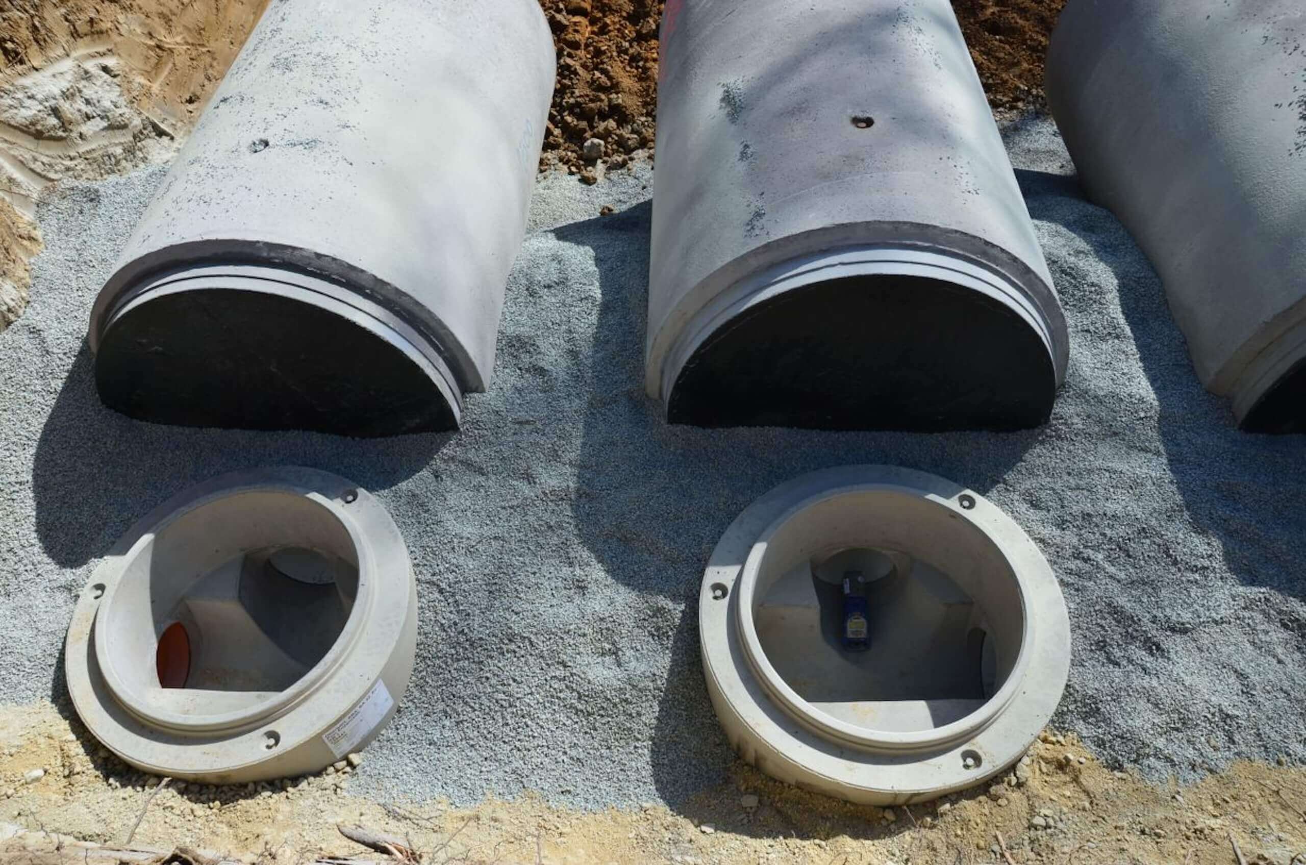 Betonrohre für Kanalbau auf Kiesbett vorbereitet, Installation in der Baugrube.