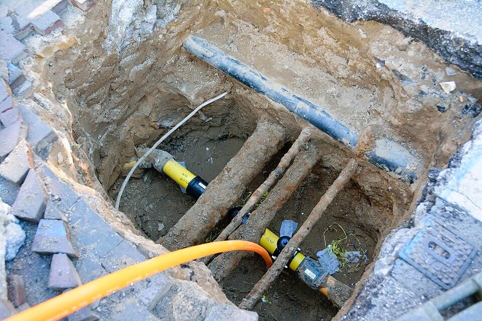 Baugrube mit freigelegten Rohren, Bauarbeiten an Versorgungsleitungen, Infrastruktur Reparatur.